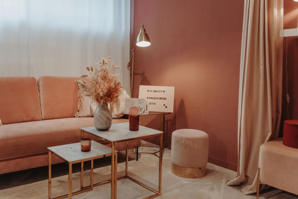 Lounge-Separée der maleika Brautboutique Krefeld mit rosé Samtsofa, goldenem Beistelltisch und Trockenblumen